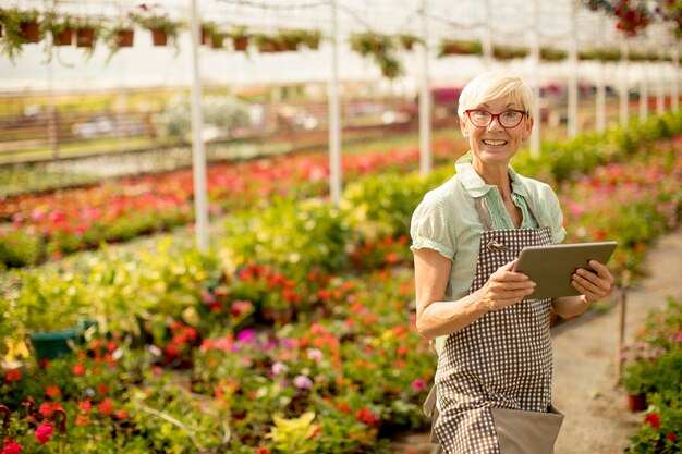 Femme aînée, utilisation, tablette, dans, jardin fleuri