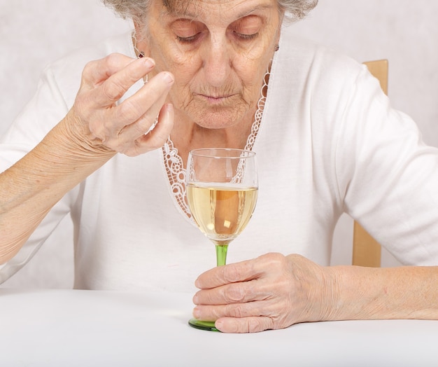 Femme aînée avec un verre de vin blanc