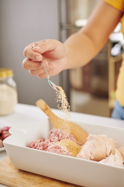 Femme ajoutant des espèces à la viande hachée