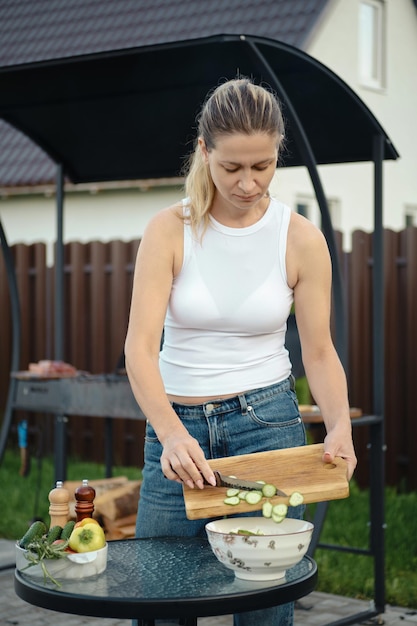 Photo femme ajoutant des tranches de concombre dans un bol