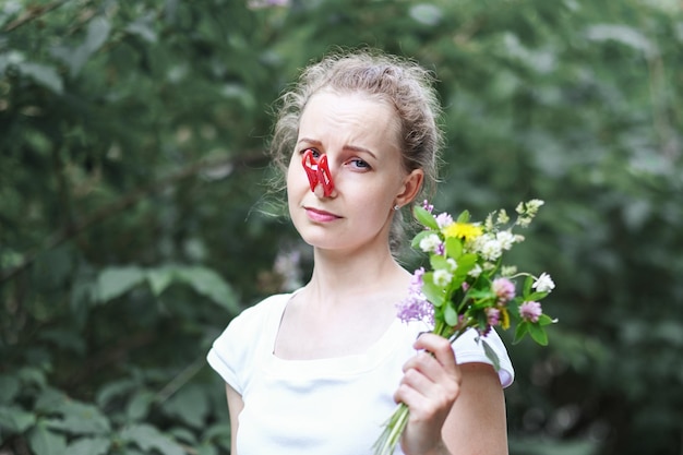 La femme d'allergie a pressé son nez avec une pince à linge pour ne pas éternuer du pollen des fleurs