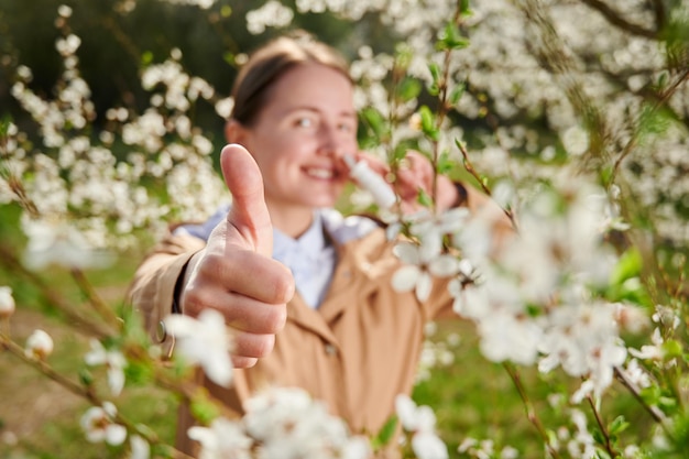 Photo femme allergique souffrant d'allergie saisonnière au printemps posant dans un jardin en fleurs au printemps