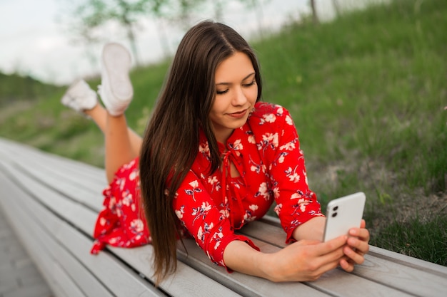 femme allongée sur un banc avec un téléphone portable