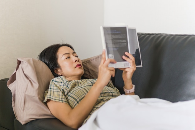 Femme allongée sur le canapé et lisant un concept de quarantaine de livre