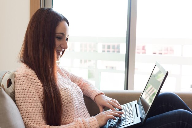 Femme allongée sur un canapé avec un ordinateur portable