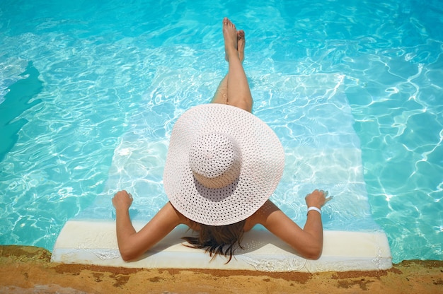 Femme allongée sur une chaise longue dans la piscine à l&#39;hôtel