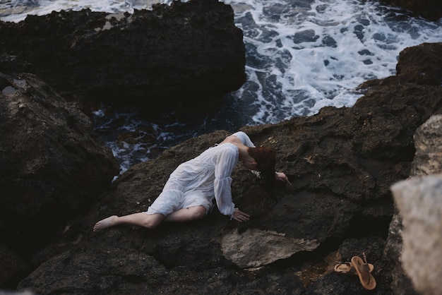 Femme allongée sur le dos sur une nature rocheuse au bord de la mer