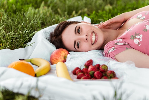 Femme allongée sur un drap blanc, souriant avec des dents blanches