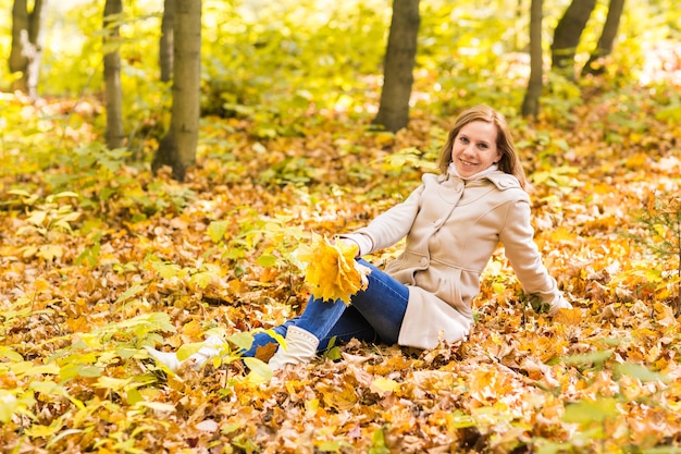 Femme allongée sur les feuilles d'automne, portrait en plein air.