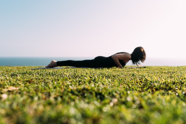 Une femme allongée sur l'herbe pratiquant le yoga est floue. Copier l'espace