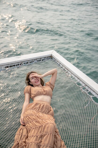 Femme allongée sur une jetée avec fond de mer, s'asseoir sur le filet au bord de la mer.