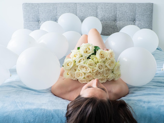 Femme allongée sur le lit avec des décorations avec des ballons pour la fête d'anniversaire