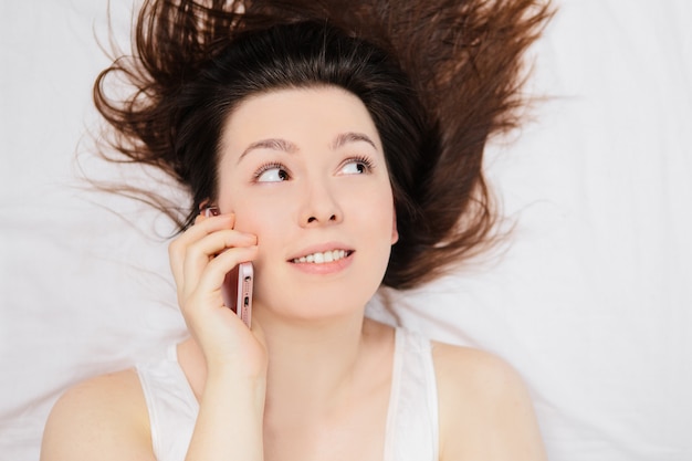 femme allongée sur le lit et parler au téléphone.