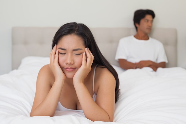 Femme allongée sur le lit avec son petit ami assis