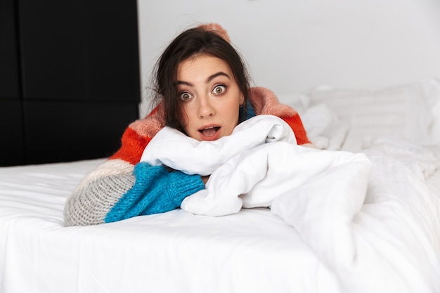 femme allongée sur le lit avec les yeux ouverts avec une expression de surprise