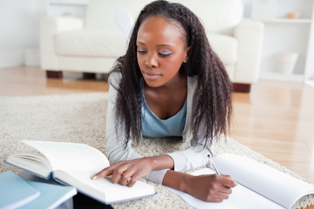 Femme allongée sur le sol à faire ses devoirs