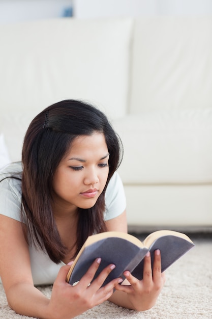 Femme allongée sur le sol en lisant un livre