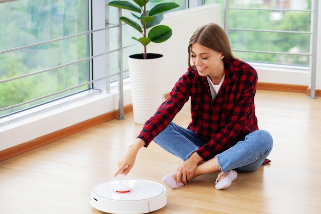 Une femme allume un aspirateur robot intelligent.