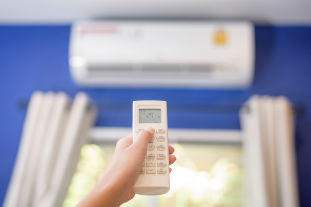 Femme allume le climatiseur à la maison