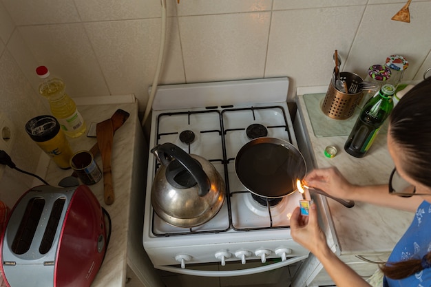 Femme allume la cuisinière à gaz avec des allumettes