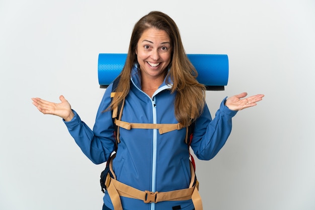 Femme d'alpiniste d'âge moyen avec un gros sac à dos sur un mur isolé avec une expression faciale choquée