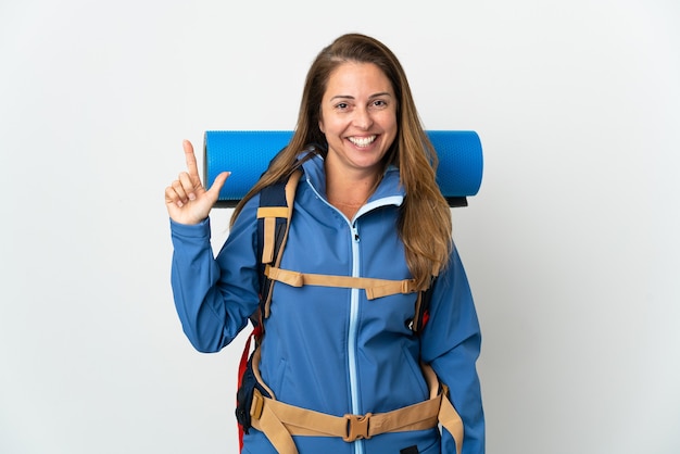 Femme d'alpiniste d'âge moyen avec un gros sac à dos sur un mur isolé pointant vers le haut une excellente idée