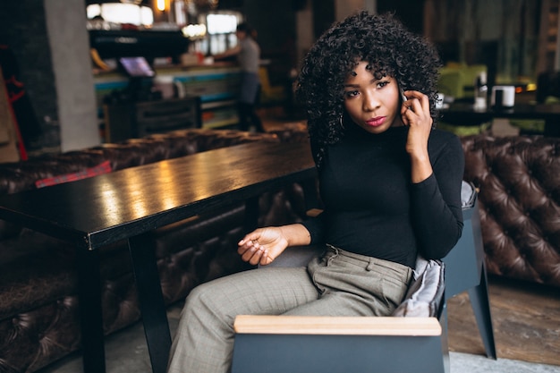 Femme américaine afro avec téléphone au café