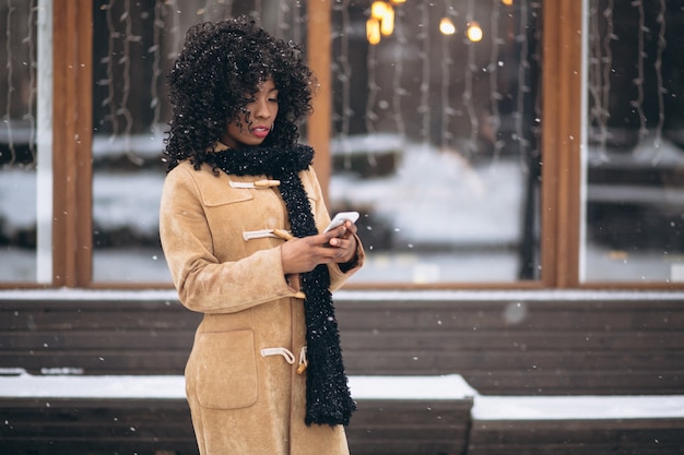 Femme américaine afro avec téléphone en hiver