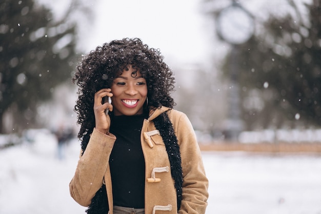 Femme américaine afro avec téléphone en hiver