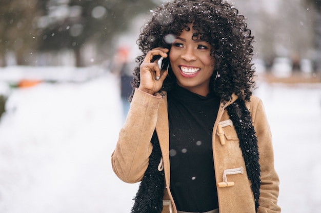 Femme américaine afro avec téléphone en hiver