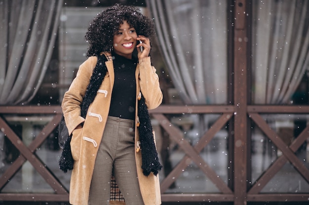 Femme américaine afro avec téléphone en hiver