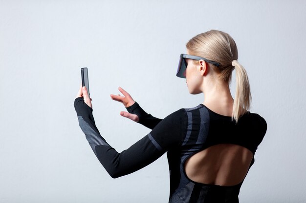 Femme Android dans des lunettes VR et téléphone mobile sur fond blanc.