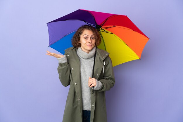 Femme anglaise tenant un parapluie isolé ayant des doutes tout en levant les mains