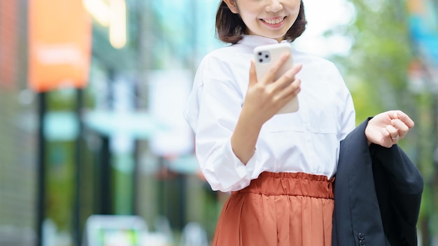 Femme anonyme tenant un smartphone à l'extérieur