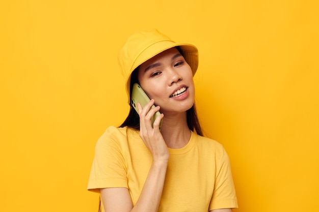 Femme d'apparence asiatique parlant au téléphone posant la mode fond jaune inchangé