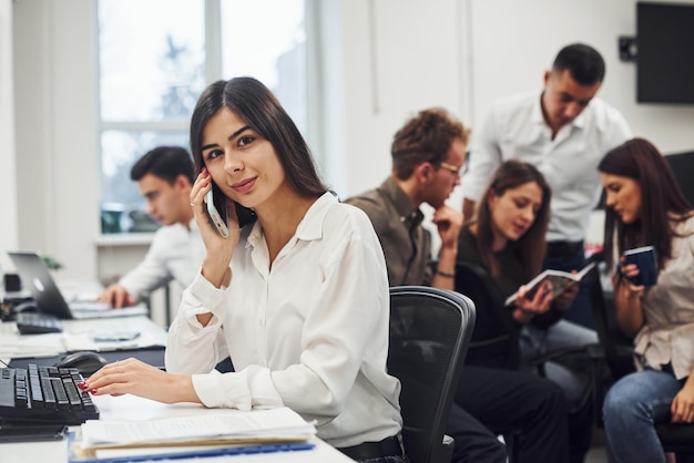 La femme a un appel. Jeunes gens d'affaires travaillant ensemble dans le bureau moderne.