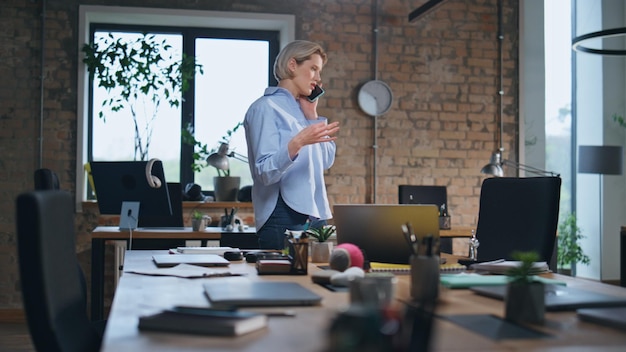 Femme appelant un bureau vide marchant près de la table de conférence femme d'affaires parlant