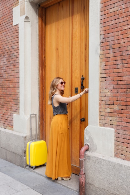 Femme appelant à son nouvel appartement portant une valise dans la ville