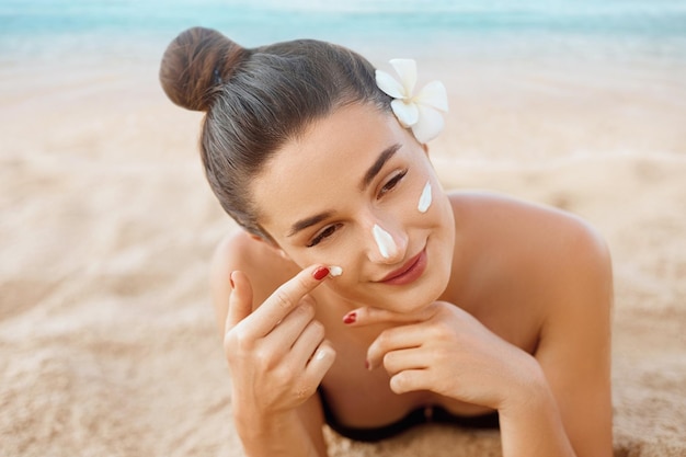 Femme appliquant sur beautifu sur la crème solaire pour le visage