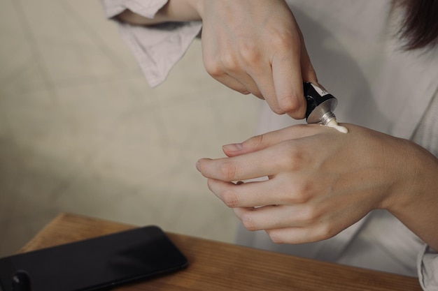 femme appliquant une crème hydratante pour les mains du tube tout en faisant un traitement quotidien de soins de la peau