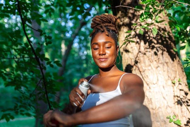 Femme appliquant un insectifuge contre les moustiques et les tiques sur ses bras lors d'une randonnée dans la nature Protection de la peau contre les piqûres d'insectes