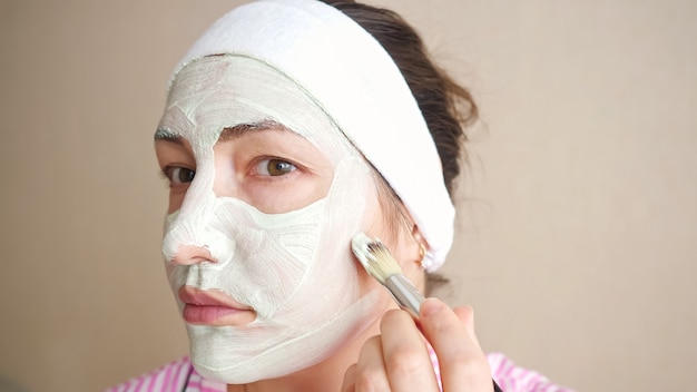 Femme appliquant un masque avec un pinceau pour faire face.