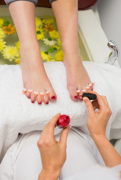 Femme appliquant vernis à ongles aux ongles des orteils au centre de spa