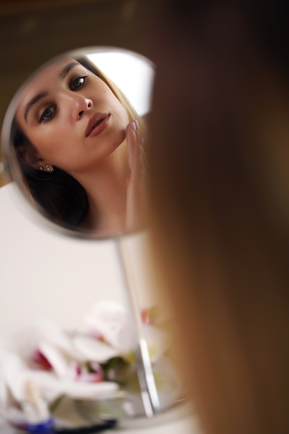 Femme applique le maquillage dans la salle de bain