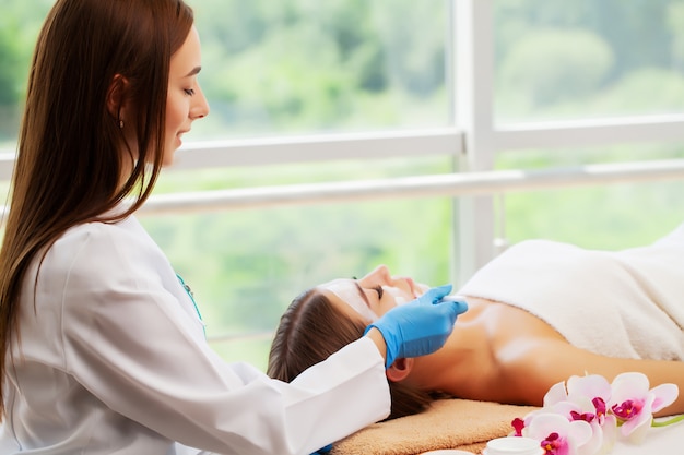 La femme applique un masque spa pour hydrater et prendre soin de la peau en salon de beauté