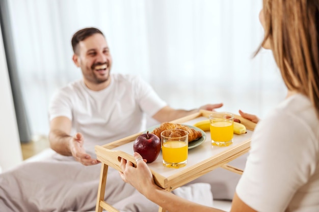 Une femme apporte le petit déjeuner dans le lit à son mari