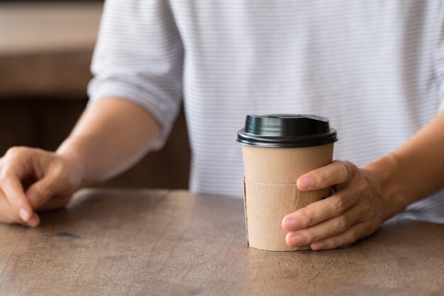 Femme appréciant la boisson de réchauffement, café en retard dans la tasse de papier