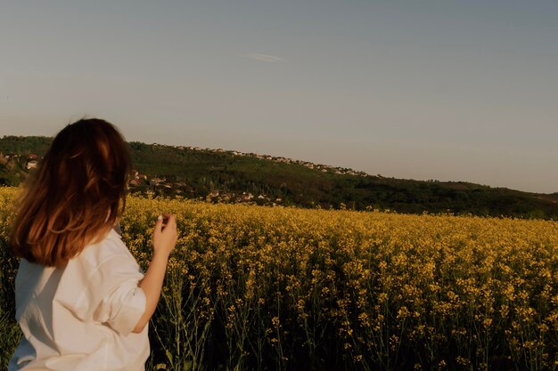 Femme appréciant le coucher du soleil dans le champ