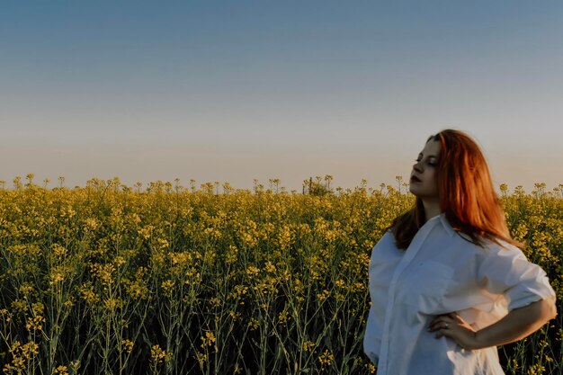 Femme appréciant le coucher du soleil dans le champ