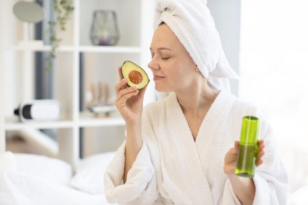 Femme appréciant l'huile faciale d'avocat pendant la journée de spa à domicile